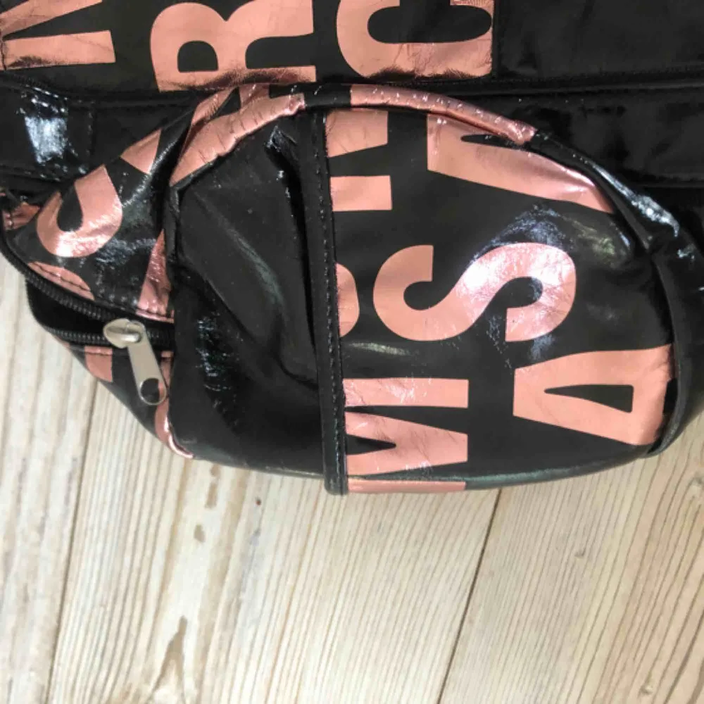 En snygg väska med bokstäver som motiv i rosa, har två fickor på utsidan som man kan se på tredje bilden. Har även en ficka på insidan. . Väskor.
