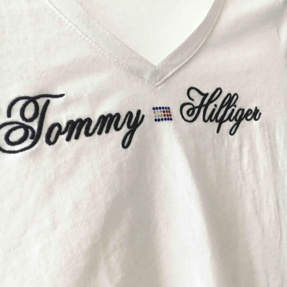 Vit v-ringad T-shirt med broderat Tommy Hilfiger. Fint skick! 100kr exkl frakt. T-shirts.