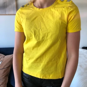 Gul tisha från Zara - Gul t-shirt från Zara med silverknappsdetaljer. Storlek S. Finns att hämta i Lund/Malmö annars tillkommer frakt 