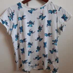 Stitch t-shirt - T-shirt med stitchmotiv och korta ärmar. Välanvänd, därav priset. Skön i materialet men för kort för mig att använda som en vanlig t-shirt. Frakt står köparen för. 