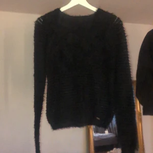 Svart stickad/fluffig tröja - En svart stickad/fluffig tröja. Den är randig i materialet ner till.