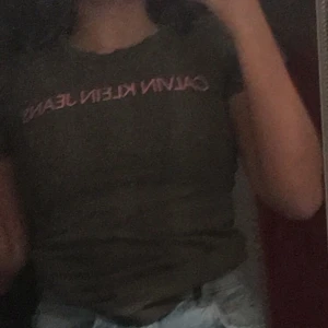 Ck t-shirt - Mörk grön ck tröja med rosa text där det står ”Calvin klein Jeans”. Väldigt bra skick - använd 1-2 gånger. Säljer för den inte kommer till användning