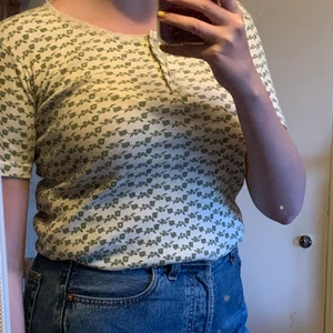 Grönblommig ribbad tröja 90-tal - Vit ribbad tröja med gröna blommor på från 90-talet. Spetskant uppe vid halsen och den är i fint skick. Visas på en M. 