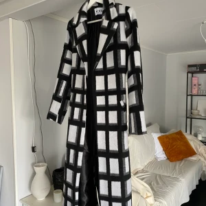 Rutig kappa - Svart och vit rutig kappa med skärp. Använd bara ett fåtal gånger. Superfint skick! Frakt tillkommer.