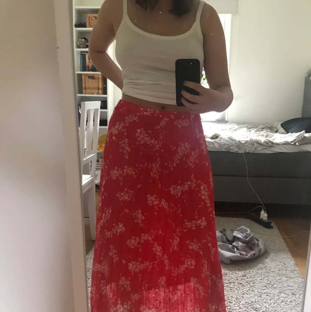 Röd och blommig plisserad kjol från Lindex, endast använd några gånger och är därför i superfint skick. Är i storlek S men passar definitivt M likaså eftersom att den har ett elastiskt midjeband💕. Kjolar.