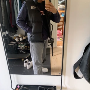 TNF retro nuptse väst - Färg svart! Lite missvisande på första bilden då det är svårt att få exakta färgen under scenlampa   •Modell: Herr •Storlek S  •Skick: 9/10 -Luva i kragen  Nypris: 2400 Pris: 1000 + 63kr frakt 