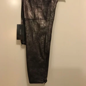  - Bronze leggings in faux mocha leather. Hidden zipper at the bottom. NEW, with tags Size M & XS