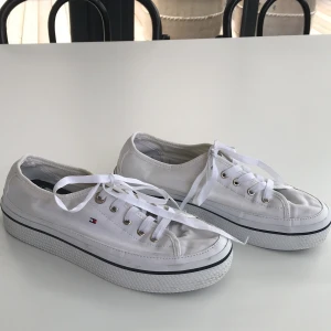 Tommy Hilfiger skor - Ett par fina vita Tommy Hilfiger tygskor. Använda ett par gånger men är hela och rena. De är även nyligen tvättade.