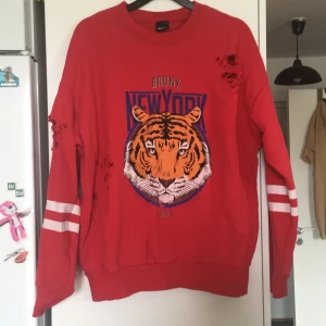 Tröja stl M - Röd tjöja med tiger. Muddar på både ärmar och vid halsen och tröjkanten. 