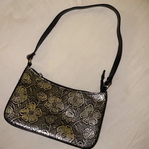 Baguettebag  - Baguettebag som är svart och silvriga blommor. Jättebra storlek och med fack inuti. Frakt tillkommer💕 