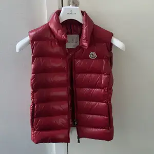 Röd moncler väst. Modell: Ghany, köpt på NK. Sparsamt använd. Intressekoll! Älskar den mörkare röda färgen! Passar xs/s. Endast seriösa bud! FINNS INGA SKADOR ELLER DEFEKTER DÅ JAG INTE HAR ANVÄNT DEN MYCKET O DEN FÖR DET MESTA HAR HÄNGT I GADEROBEN. 