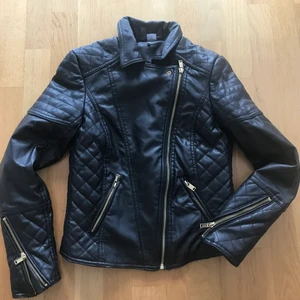 Kort fusk skinn med avtagbar krage i ’oäkta’ päls - Nästan oanvänd kort jacka som ser ut som skin, men är 100% polyester. Avtagbar krage i ’oäkta’ päls. Storlek 36. Färg svart. 