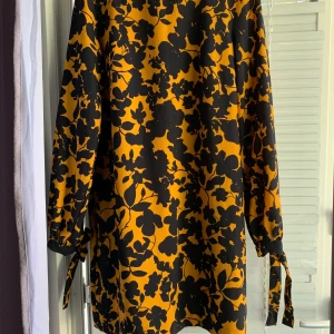 Ny! Snygg H&M klänning - Jättefin klänning med fina höstliga färger lite lös rak modell med långa ärmar. Från H&M i str. 36-38. Har hängt i skåpet och aldrig använt. I nyskick. Knälång. Gul / mörkblå färg.