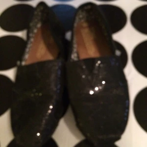  - Välanvända Toms i svart glitter.
Frakt tillkommer.
