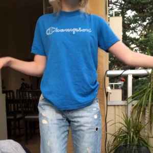 Blå champion t-shirt - Blå champion t-shirt köpt på secondhand. Texten är lite sprucken men inte farligt mycket. Den är storlek 152 i barnstorlek men sitter som en M.