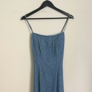  - Jättefin balklänning i ljusblått tyg och pärlbroderier på hela klänningen. Slits på båda sidorna. Säljer pgr av flytt och behöver minska garderoben. Köpt på Beyond Retro 