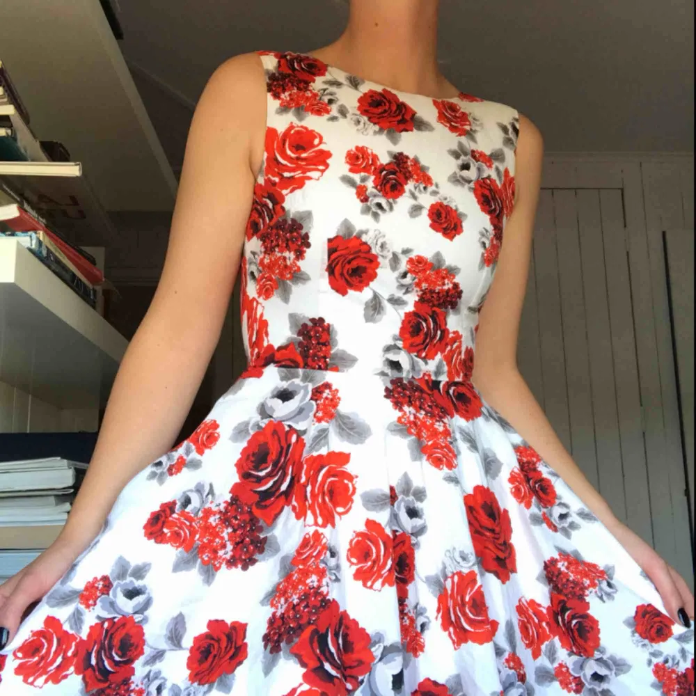 Kort klänning i 50-talsmodell. Bomullssatin med djupt röda rosor på. Båtringning i halsen och klockad kjol. Köparen står för frakt eller möts i Gbg ✨. Klänningar.