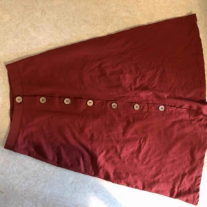  - Superfin roströd kjol med träknappar, faller fint då den är lite klockad. Går just ovanför knät på mig som är 168cm