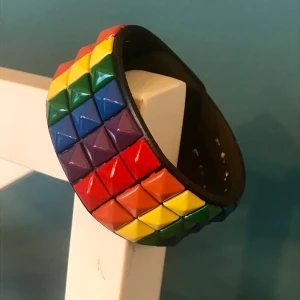 Regnbågsfärgat nitarmband - 20 cm runt handleden. Jag har smala handleder 16 cm, så den är för stor för mig. Annars knappt använd. I fint skick! Köp nu 😊