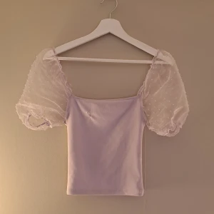 Ljus lila topp - Topp med puff ärmar har en defekt på framsidan annars hel  Väldigt stretchig!