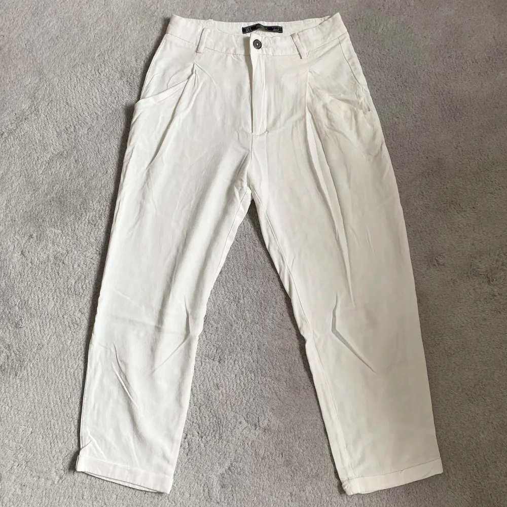 Vita ankellånga byxor från Zara i storlek S. Löst och flowigt material med två fickor fram och två fake fickor bak. Lösa i passformen och snygg modell. Innerbenslängd: Ca 60 cm. Jeans & Byxor.