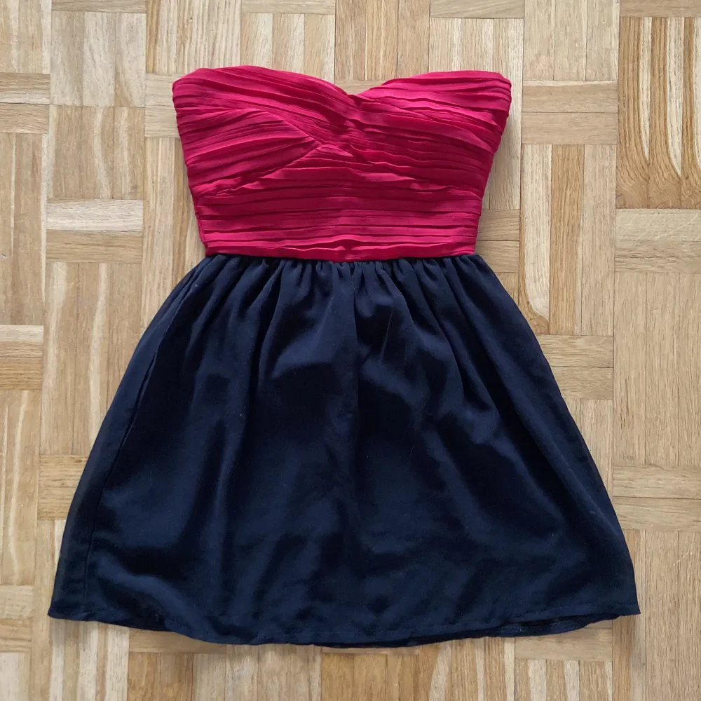 En festklänning som aldrig är använd en gång. Röd top med svart kjol, man behöver ingen bh. Kjolen är två lager. . Klänningar.