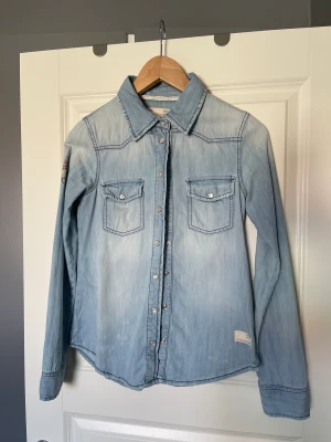 Jeansskjorta - Säljer denna superfina jeansskjorta som tyvärr blivit för liten. Funkar perfekt att snvända som den är eller som en overshirt! Nyskick! Köpare står för frakt