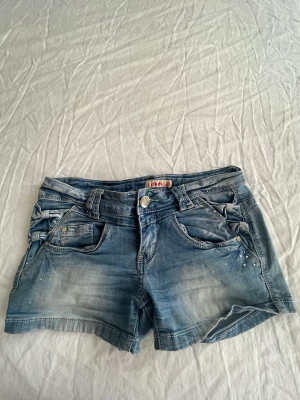 Lågmidjade shorts - Säljer min mammas gamla vintage lågmidjade shorts från märket idodo😁 så coola som verkligen är unika med rosetter på sidan (bild 3) och små diamanter på sidan🤩🤩 storlek 36/S