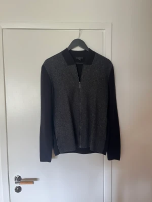 Cos cardigan - Säljer min feta full zip tröja från cos, en modell som är slutsåld sedan år tillbaka. Storlek S i bra skick. Hel svart på baksidan samt ärmar, grått ull på framsida. Perfekt nu till hösten, hojta till för mer bilder eller info! 