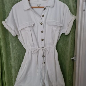 Vit playsuit - Snygg vit playsuit från Nelly! Playsuiten har ett innertyg och är därmed inte alls genomskinande. Använd en gång på min konfa avslutning. Om du har några frågor är det bara att skicka iväg ett meddelande!  Längd: 70 cm Bredd: 50 cm