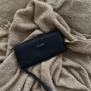 Guess plånbok svart - Säljer min guess plånbok som jag aldrig har använt, stor och rymlig med många fack. Den är hel svart med silvriga detaljer. Nypris 600 ungefär.