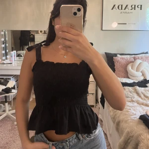 Svart volangtopp - En svart volangtopp köpt från h&m, i jätte fint skick, använd 2-3 ggr. I storlek S, passar även xs då banden kan knytas i önskad längd.