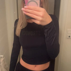 Stronger träningströja - Träningströja från stronger, står stronger ifram och har deras ”logga” som är 2 sträck på armen. På ryggen är de som näthål vilket är perfekt för träning. 💕💕 säljer även stronger tränings thigths i en annan annons