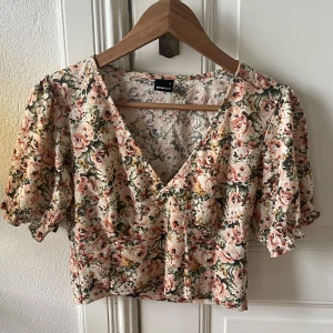 Topp - Blommig topp från GinaTricot. Lite croppad och urringad och har lite puffiga ärmar. Finns matchande shorts till.