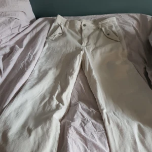 Jag har inte amvänt dem så mycket så dem är inte så slitna. - Dem är vita högmidjade jeans  och har väldigt många fickor två bak och två fram. Dem är väldigt vuda där nereoch lite tajtare vid låren.