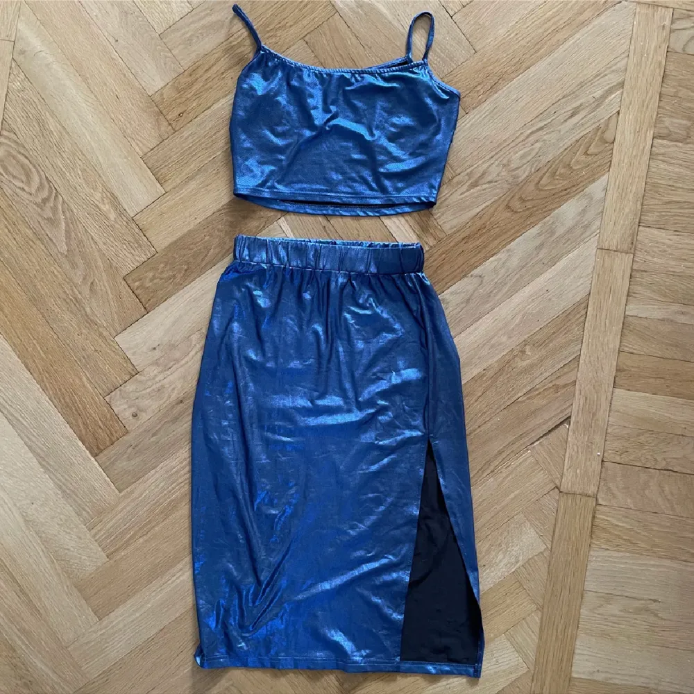 Topp + kjol i metallisk blå. Båda superstretchiga och mjuka, använda ett fåtal gånger. Kjolen är midi med slit. . Klänningar.