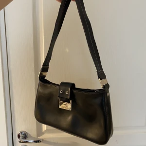 Väska - Svart baguette väska. Har fastnat lite klister på spännet men kan tvättas bort! Fransat sig något på bandet. Från next. 