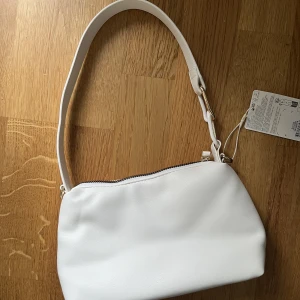 Vit axelväska - Säljer denna oanvända vita axelväska från Primark med prislappen kvar. Enkel i design men fin och väldigt rymlig och tjock i materialet! Priset kan diskuteras!