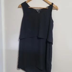 Svart klänning - Svart elegant & stilren klänning med en volang upptill. Oanvänd. Passar om man ska på fest med gatsby-tema