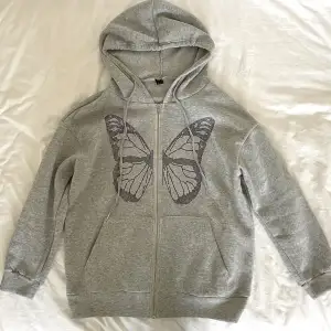 Populär grå zip up hoodie från shein med en fjäril på. Använd få gånger, inga defekter och är i nyskick. Köpt för 219kr men säljer för 50kr.