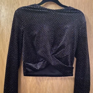 Magtröja - Kort långärmad tröja i glitter tyg. 