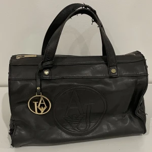 Vintage armani väska🌟 - En rymlig väska från armani jeans som är köpt secondhand, men jag har endast använt den en gång. Den är lite sliten så det är bara att komma med prisförslag. Hör av dig om du vill ha fler bilder eller har några frågor🤗