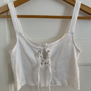 Vit topp med knytdetalj - Väldigt gullig topp med knytdetalj i fram. Storlek xs men passar även en s. Bra skick.
