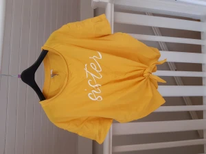 Croppad T-shirt med knytning  - Gul croppad tröja från H&M med knytning fram storlek XL. I fint skick och mjukt material.