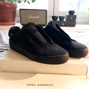 Axel Ariagto Clean 360 Laceless - Jättepopulära svarta mockaskor från axel arigato. Mockan är lite sliten men de är ändå i gott skick. Du får med skokartongen och dustbag. Nypris 2550kr men säljer för 1200kr. Vid snabbt köp kan du få dem för 1100kr. Skriv privat för fler bilder.
