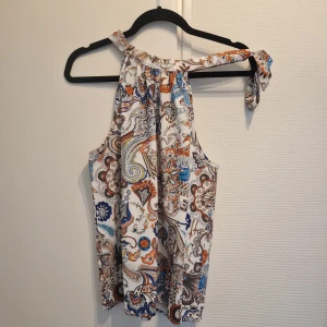 Paisleymönstrad blus - Paisleymönstrad blus med knyt i halsen utan ärmar.