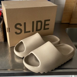 Yeezy slide pure (2020 modell) - Säljer mina Yeezy slides för har ingen användning av dom, skick 8/10 dom är lite spruckna på framsidan men de syns knappt, storlek 44 men passa även till 42,43 för sliden är liten i storlek.