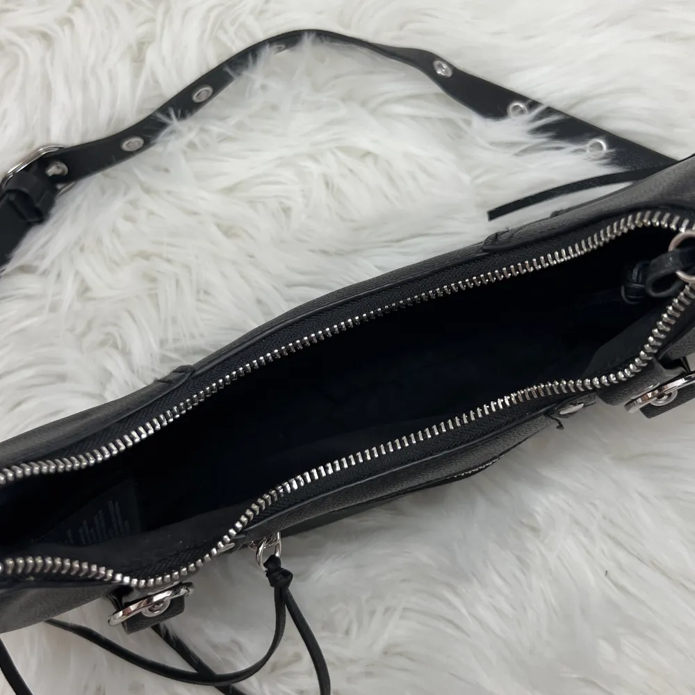 Svart handväska från H&M med silvriga detaljer. Man kan justera bandet på vöskan. Dragkedja och mycket utrymme. Knappt använd.. Väskor.