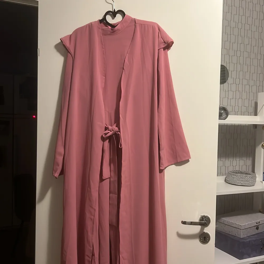 Rosa jumpsuit med en kortärmad lång abaya över och ett rosa bälte till.. Klänningar.
