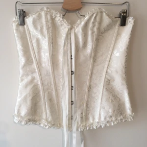 Vit Korsett - Korsett med hakar fram och snörning bak. Köpt secondhand. Säljer en liknande i svart!